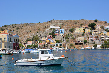 Fototapeta na wymiar white boat in port of greek island Symi with waterfront on background