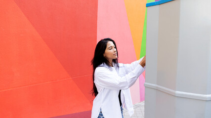 young woman putting letters in the mailbox with colorful background