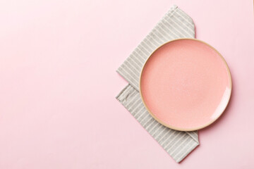 Top view on colored background empty round pink plate on tablecloth for food. Empty dish on napkin with space for your design