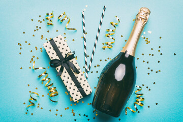 bottle of champagne with glasses and colorful confetti on colored background. top view flay lay