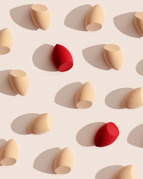 Geometric pattern from makeup sponges for foundation cream on beige background with dark shadows. Beauty blender red and beige. Fashion Flat lay cosmetic sponge, top view graphic layout,
