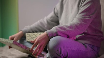 A girl opens a box with a gift while sitting on the sofa at home. A gift from a loved one. A surprise for Christmas