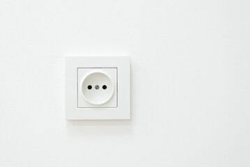 Electric outlet on a white wall. White inked wall with electric socket
