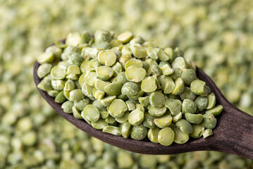 Spoon with green pea. Close up shot of black wooden spoon with pea grain