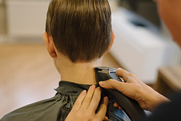 Woman cuts hair of boy at home. Homemade haircut