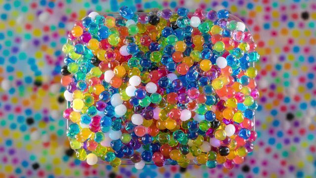 4K Time Lapse of Water beads growing in water close-up, top view. Texture of Hydrogel jelly balls - many colorful orbeez.