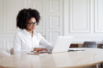 A female freelance designer with glasses working in the office prints a message to the client by mail. The manager uses a computer to report online.