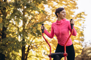 Woman exercising in park using equipment