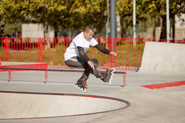 Mature male inline roller training in public skate park. Practicing jumps, tricks. Concept of...