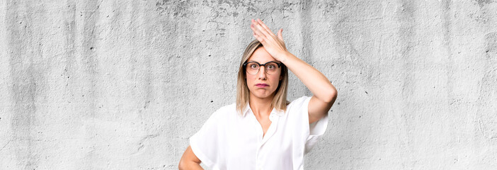 blonde adult woman raising palm to forehead thinking oops, after making a stupid mistake or...