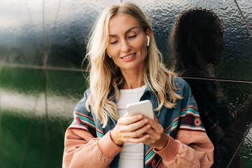 Blond woman outdoors text message in mobile phone.