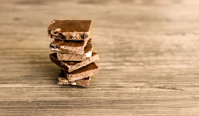 Broken pieces of chocolate on a wooden background