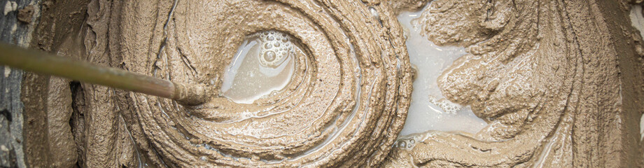 mixing cement adhesive with a mixer in a bucket close-up, texture of a mixed mortar