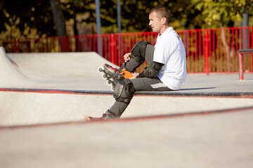 One man, male roller skater on rollerblades training at modern skate park, outdoors. Action,...