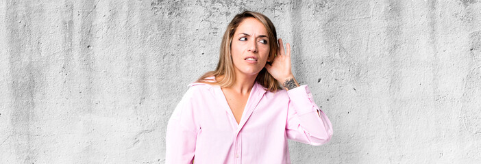 blonde adult woman looking serious and curious, listening, trying to hear a secret conversation or...