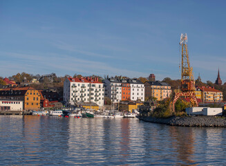 Obraz premium Harbor and wharf view, apartment buildings on the islands Djurgården and Beckholmen a colorful autumn day in Stockholm
