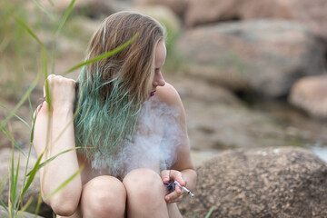Young woman with a cigarette on nature background