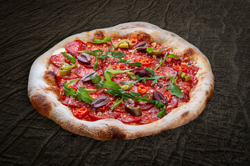 Pizza Diavolo with chorizo, rucola, jalapeno, chili, kalamata, pesto. Neapolitan round pizza on wood background
