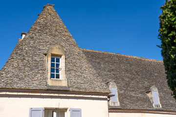 The Marqueyssac Chateau (Les Jardins de Marqueyssac) aged roof with hand cut stone tiles, clear blue sky, Dordogne France