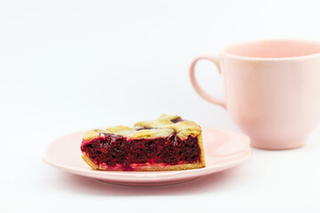 Fresh cherry pie on pink plate with cup on white background