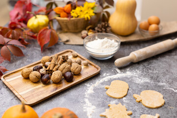 Fototapeta na wymiar Cooking cookies in the form of leaves on the kitchen table with autumn decor. flat layout. Shortcrust pastry cookies for Thanksgiving and Halloween. wooden rolling pin, flour, dough, leaves, decor.