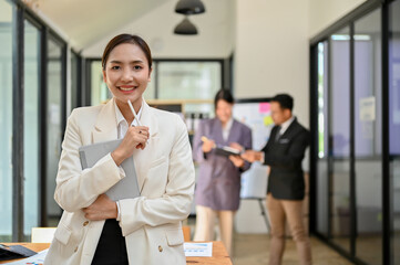 Beautiful and successful Asian businesswoman or female boss stands in her company