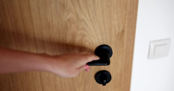 Person opens wooden door with black handle closeup