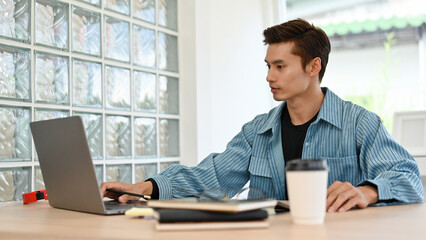 Smart Asian businessman or male office worker working on his tasks on laptop in the office.