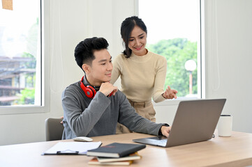 Professional young Asian male office employee working with his female colleague
