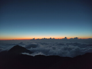 Sunset at the top of the mountain above the clouds. Above the clouds Aerial view of mountain peak in fog. Beautiful landscape with high rocks, sky.  mountain valley in low clouds. Foggy hills