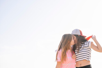 Two girlfriends kissing and waving LGBT pride flag.