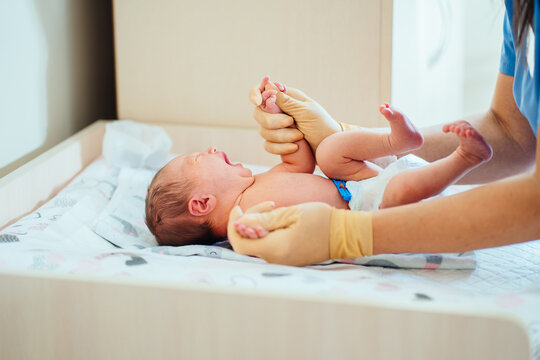 Adorable Newborn Baby 3 Day Old Girl In Diaper Check Up Examines, Warm Up, Massaging And Calming Down A Crying Baby By Unrecognizable Pediatrician Doctor In Hospital.