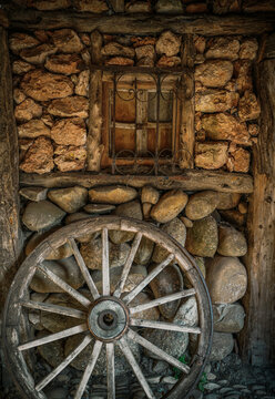 Old cart wheel, in a rustic town in Spain, Vintage style, with old stone and wood background,