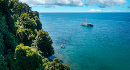 Aerial view of a sailing boat anchored off a rocky coast
