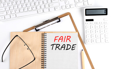 Notebook with the word FAIR TRADE with keyboard and calculator on the white background