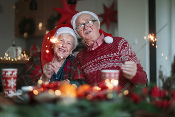 Happy senior couple celebrating Christmas Eve with sparklers.