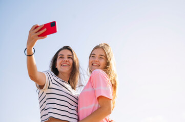 Two young girls take pictures with the smart phone.