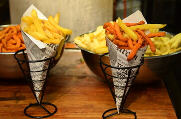 French fries close up. Belgian potatoes in vintage newspaper. Traditional fast food - fried potatoes. Large bowl with fried potatoes in the background Fries Sweet Orange Potato
