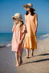 Mother and daughter walk at beach in morning.
