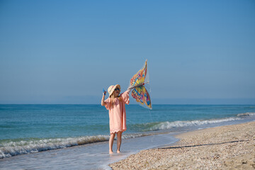 Naklejka na ściany i meble Girl with butterfly kite at sea beach