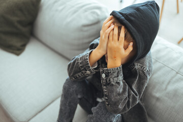 Young preteen teenager boy holding his had in his bedroom with smartphone, Cyber bullying in kid, depressed child mental health, fomo, social distancing concept. Lonely sad boy at home