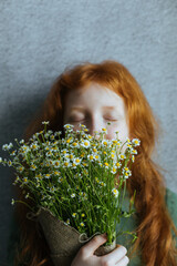 Naklejka premium Red-haired girl with a bouquet of daisies