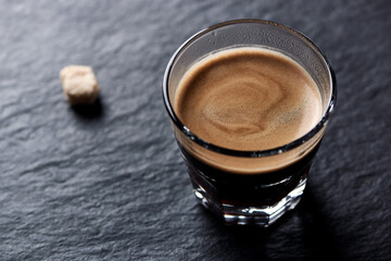 Coffee in glass cup on dark stone background. Close up.