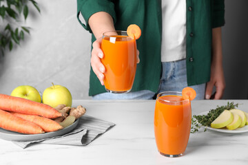 Woman holding glass with carrot juice, closeup
