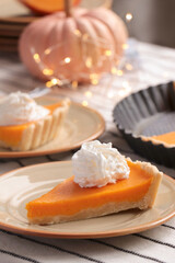 Fresh homemade pumpkin pie with whipped cream on table