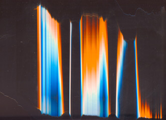 Glitch distortion. Old film. Analog noise. Orange blue white rainbow color light flare dust scratches on dark black illustration abstract background.