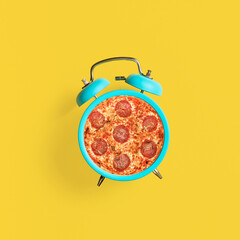 Turquoise vintage alarm clock on yellow background. Top view. Modern food concept.