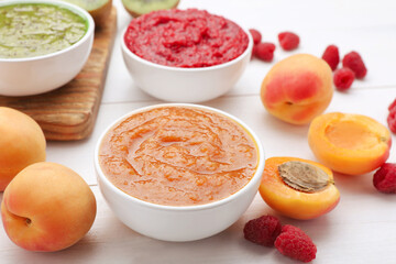 Different puree in bowls and fresh fruits on white wooden table