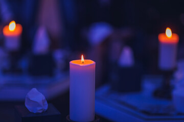 Candles are burning on the candle stand in the dark bluish back background.
