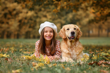 beautiful girl in the autumn park with a dog golden retriever labrador for a walk